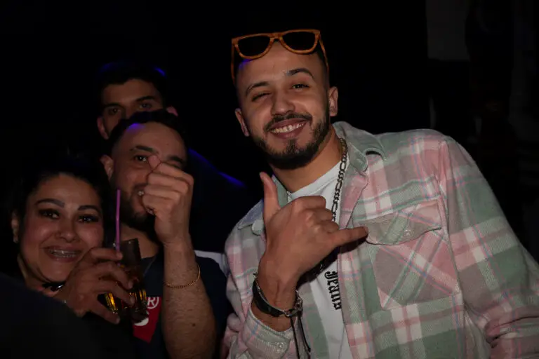 Four friends posing for the camera with one man doing the shaka hand sign